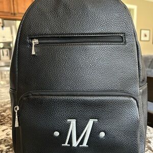 Black backpack purse with an M monogram. No tags but never used. Excellent cond.